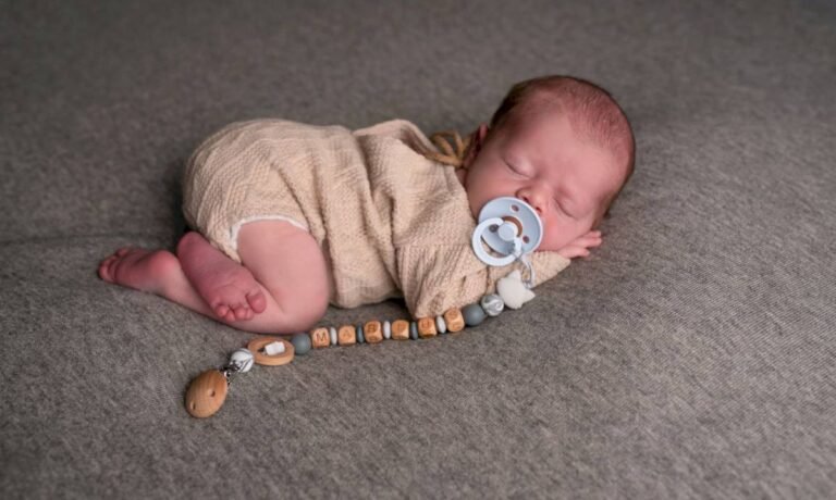 Nouveau-né endormi sur un tapis gris avec une sucette, séance photo naissance