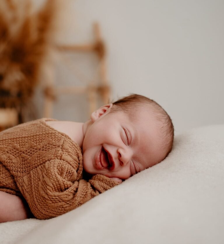Nouveau-né souriant allongé sur un plaid, séance photo bébé