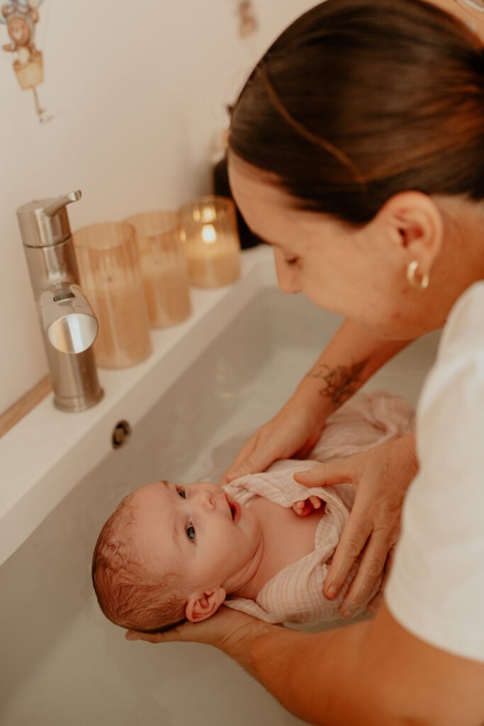Maman penchée sur son nouveau-né emmailloté dans le bain thérapeutique, bébé la regarde
