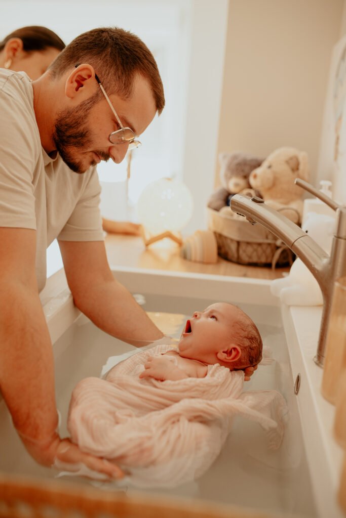 Papa souriant regardant son nouveau-né emmailloté dans l’eau du bain thérapeutique