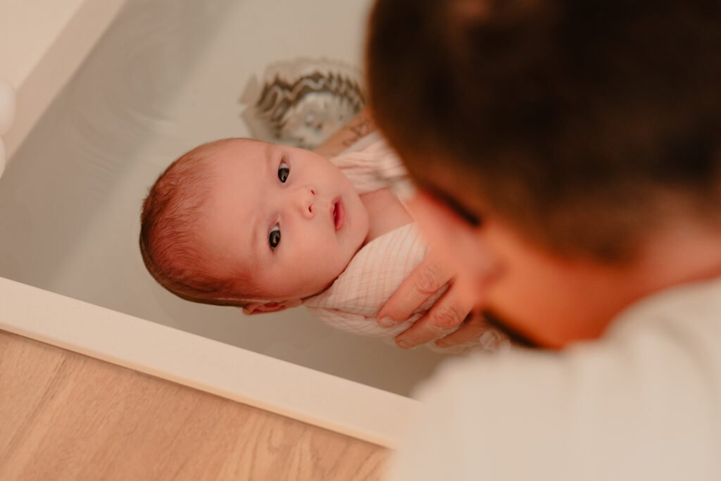 Nouveau-né éveillé, regard attentif, tenu dans l’eau du bain thérapeutique par ses parents